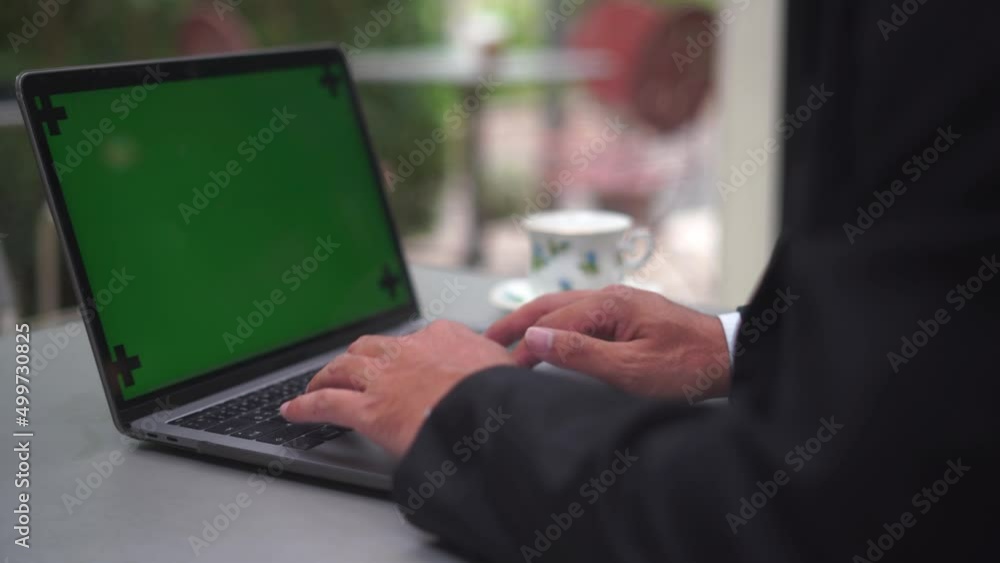 Poster Close-up of green notebook computer screen with the fingers of a man in a business suit typing on a keyboard