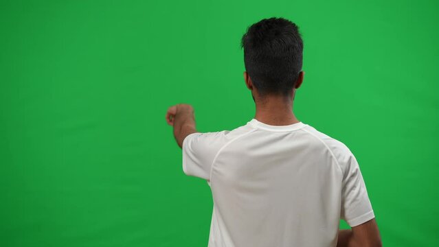 Back view Middle Eastern football coach gesturing pointing on green screen template. Concentrated serious man controlling game at chromakey background. Sport and expertise concept