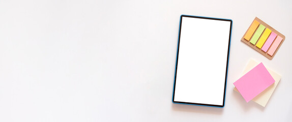 Banner with tablet with copy space, mockup on light beige background. Colorful stationery, stickers on the side. Minimalism, flat lay, top view.