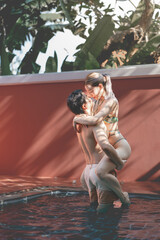 Fototapeta na wymiar Couple in love, Man carrying woman in swimming pool.