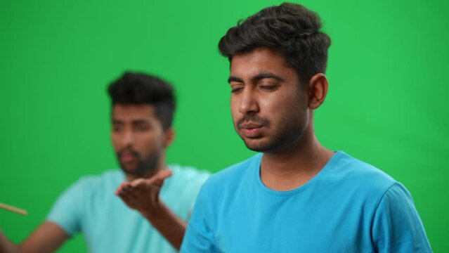 Stressed football fan gesturing holding head in hands looking back at blurred friend with German flag on green screen. portrait of dissatisfied young Middle Eastern man watching soccer game