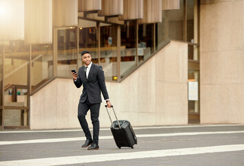 They better have flight details. Shot of a businessman walking around town with his luggage using his smartphone.