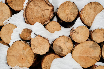Close-up of dry chopped firewood forming woodpile covered with snow that can be used as background...