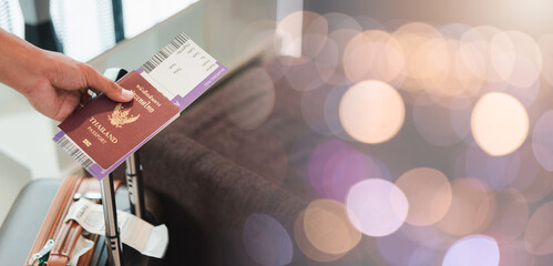 Close up hands the man going to flight with suitcase holding Thailand passport and airline ticket...