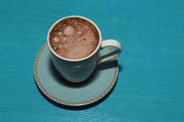 hot and sparkling chocolate in a blue ceramic cup on a wooden table from above