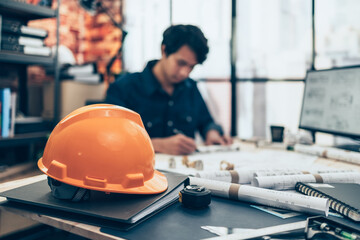 Safety hat in front of Architect engineer use pen  drawing design working on blueprint. House...