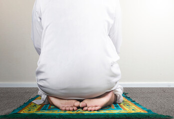 Close up view of a Muslim man in a praying position (salat) on a prayer rug