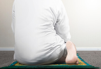 Close up view of a Muslim man in a praying position (salat) on a prayer rug