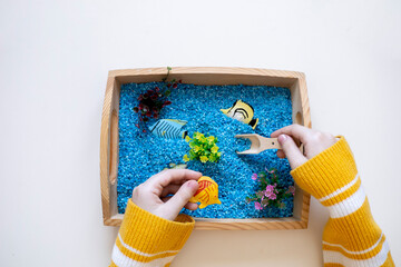 Top view of child hands, sensory box in Montessori school. Copy space