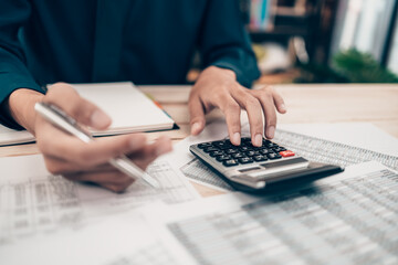 Investors working on desk office and using a calculator to calculate balance, projit, currency and cost. Accounting and  Financial concept.