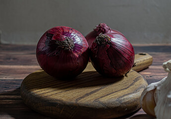 Fresh garlic bulbs and a garlic press on an old wooden board and a burlap backing.