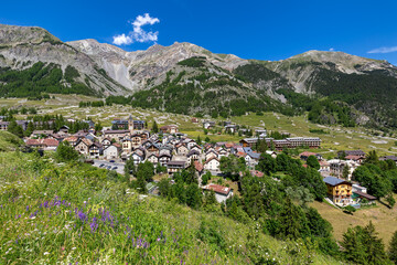 Small alpine town on the green valley among mountains in Italy.