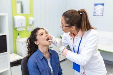 Doctor using inspection spatula to examine patient throat. ENT doctor doing throat exam of a woman. patient opened her mouth to throat check-up