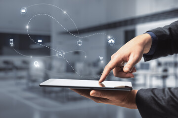 Close up of businessman hand pointing at tablet with abstract SEO and communication hologram on blurry office interior background. Double exposure.