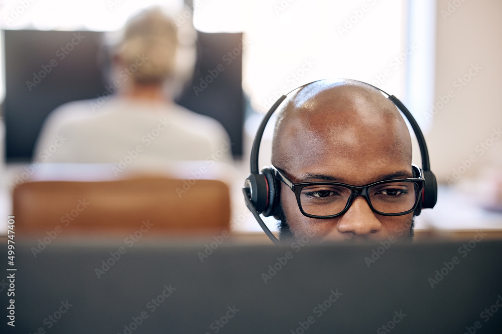 Poster Monitoring inbound calls and email inquiries. Shot of a young call centre agent working on a computer in an office.