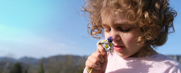 young girl smelling field flowers.