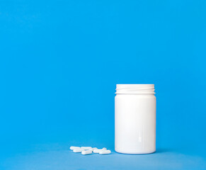 white bottle with white pills on a blue background