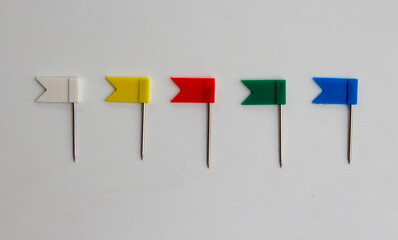 Multicolor plastic flag pins in a row on white background