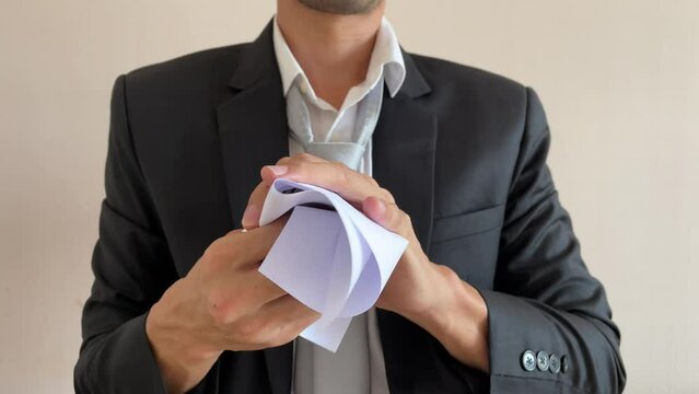 Frustrated asian businessman professional crumpling paper with written message &ldquo;IGNORED&rdquo; word. Man in suit and tie having nervous breakdown furiously throwing crumpled paper at work in office