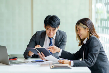Two Asian business people discuss with new startup project Idea presentation, analyze planning at office.