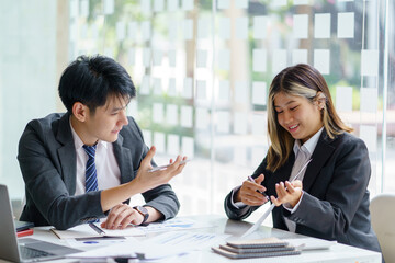 Two Asian business people discuss with new startup project Idea presentation, analyze planning at office.