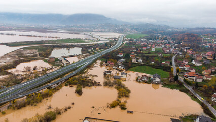Aerial drone view of torrential rain causes flash floods in residential areas. Houses and roads surrounded by water. Climate change. Heavy rainfall consequences. 
