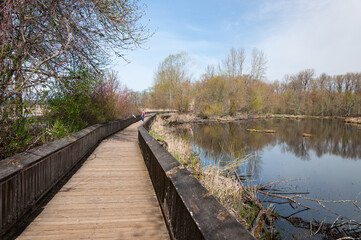 Pedestrians on wooden bridge over the lake in the Billy Frank Jr. Nisqually National Wildlife Refuge, WA, USA