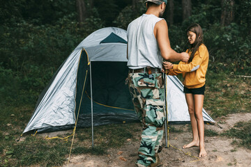 A happy father and daughter are setting up a camping tent. Family time, family rest, care