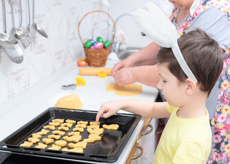 Child boy laying cookies for Easter day on a baking tray. Happy Easter concept. Process of making cookies. Cooking at home concept. Tradition home-made food