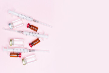 Obraz premium Syringe and vaccine against flu, coronavirus and other diseases on a pink background. Keep your health. Medical treatment concept. Top view. Flat lay. Immunity. Copy space. Place for text.