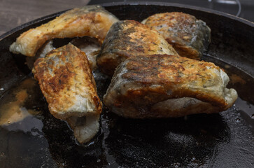 The cook fries carp fish in a frying pan on an induction stove	