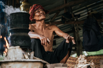 Obraz na płótnie Canvas Senior man steaming sticky rice with wood stove lifestyle in countryside