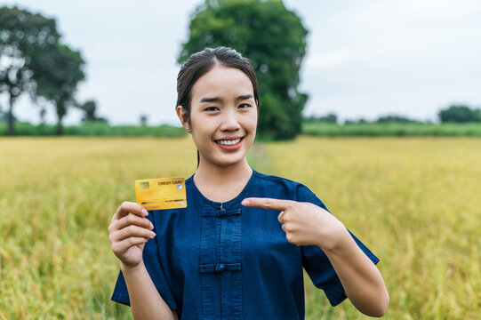 Young farmer woman with credit card in rice field