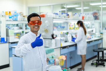 Picture portrait of a scientist smiling giving thumbs up at laboratory