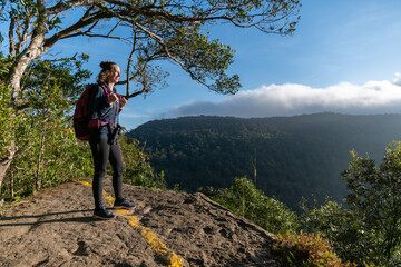 Picture of woman who is a solo traveler, is enjoying the view over top mountain in the morning