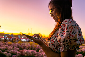 Picture of asian woman using smartphone at sunset