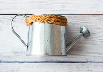 Metal silvery watering can on a white wooden background. The concept of ecology, farming, gardening © Kiryakova Anna