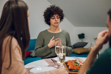 Group of friends enjoying dinner while sitting at the kitchen table together