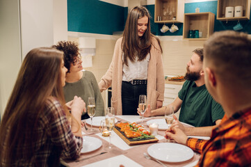 Group of friends enjoying dinner while sitting at the kitchen table together