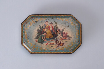Antique, printed tin box on a paper background.
