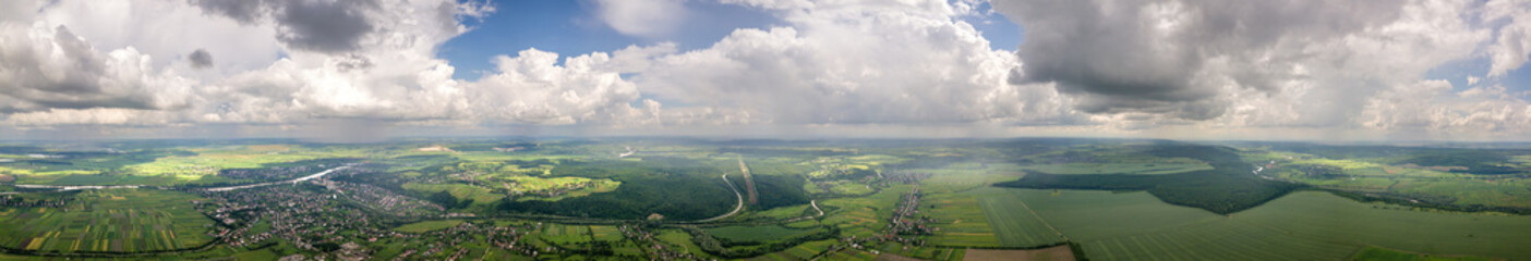 Bright landscape of white puffy cumulus clouds on blue clear sky over rural area.