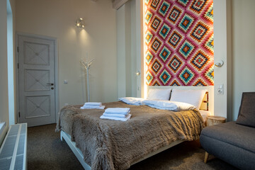 Interior of a spacious hotel bedroom with fresh linen on a big double bed. Cozy contemporary room in a modern house.