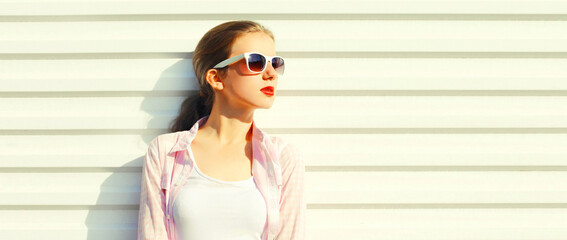 Portrait of beautiful young woman with red lipstick wearing white shirt, sunglasses on background, blank copy space for advertising text