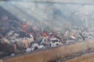 A man cooking bacon on barbecue grill. BBQ smoke. Food background. Detail of the red-hot coals.