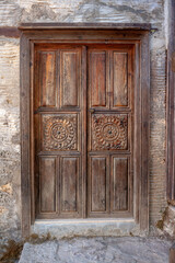 Old wooden shabby carved door. Vertical photo.
