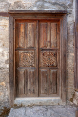 Fototapeta na wymiar Old wooden shabby carved door. Vertical photo.