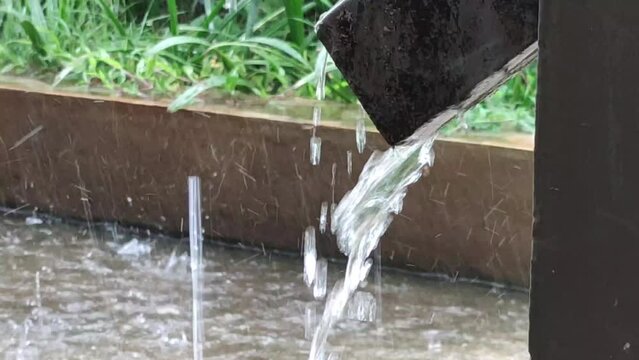 Water from waterspout flow down to the ground while raining. Raining on a rainy day, Heavy rain against green background. Rainshower on green background. Heavy rain down from the downspout.