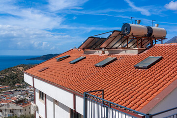 Solar water heater installed on tile roof of house for environmentally friendly heating of water....