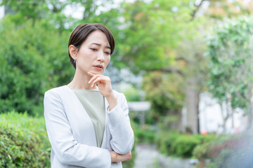 考えるビジネスウーマン（ビジネス・仕事・新緑・屋外）