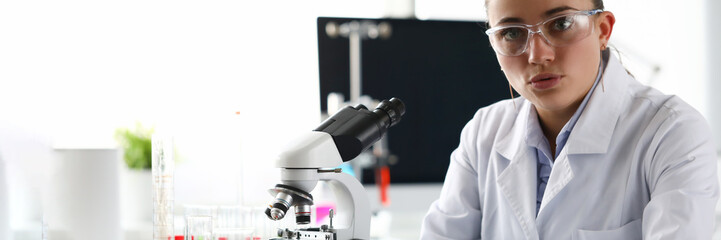 Woman scientist chemist sitting in front of microscope in laboratory